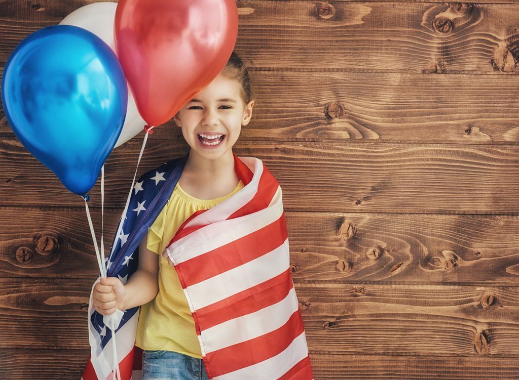 happy-girl-holding-red-white-and-blue-balloons-and-wrapped-in-an-american-flag-for-the-fourth-of-july