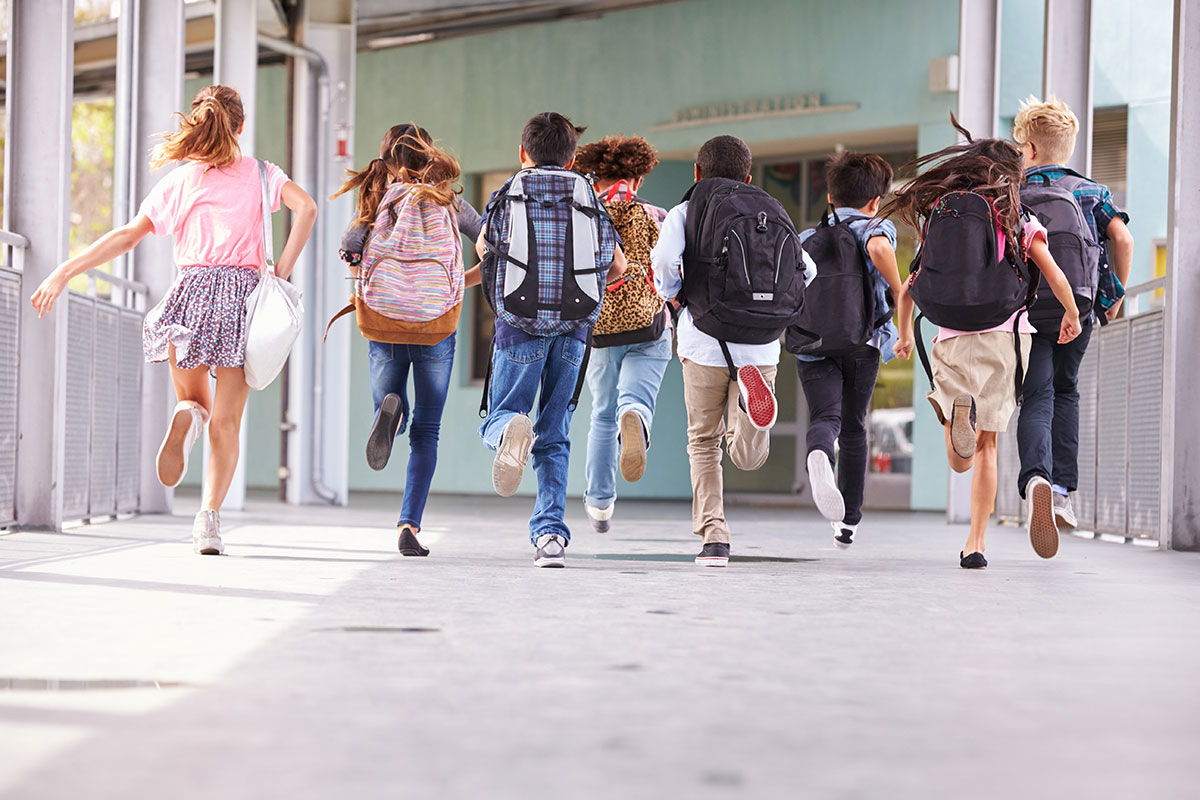 school children with large backpacks running