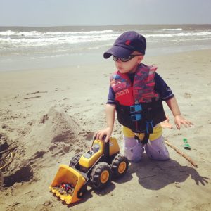 young boy playing with a truck on the beach