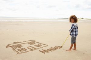 boy drawing a house in the sand
