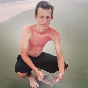 young man holding stingray on the beach