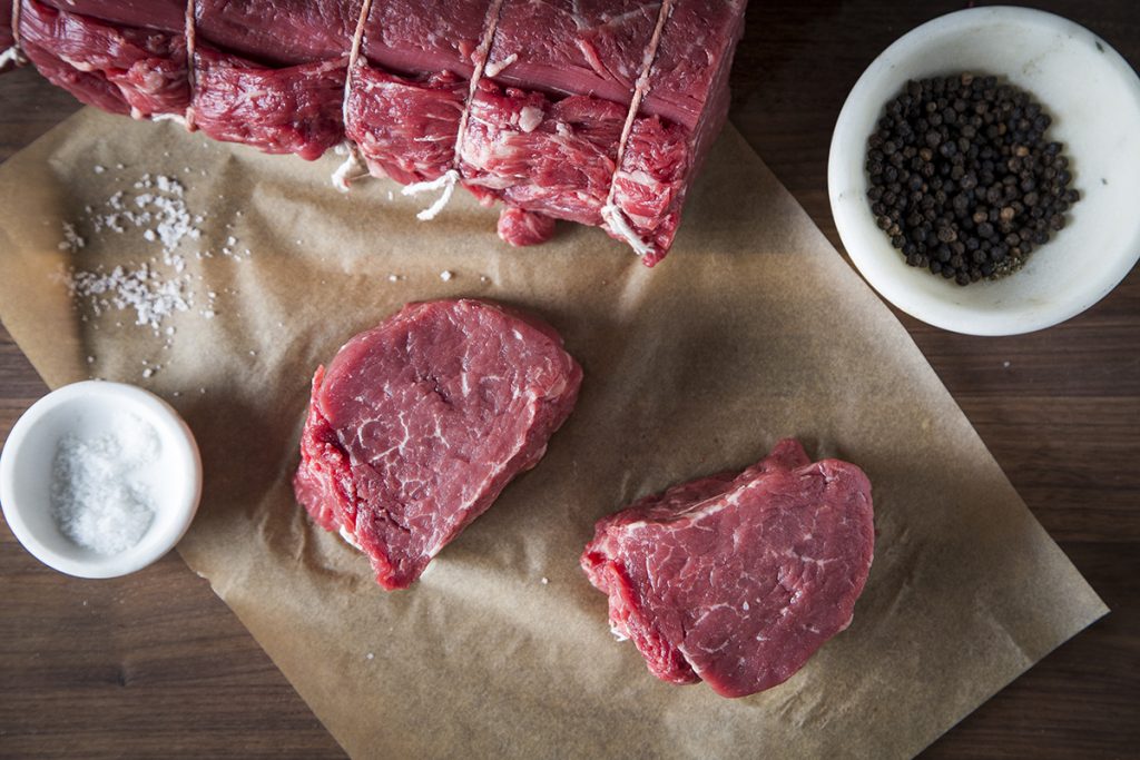 Uncooked Beef Tenderloin Filet with Salt and Peppercorn on either side of it
